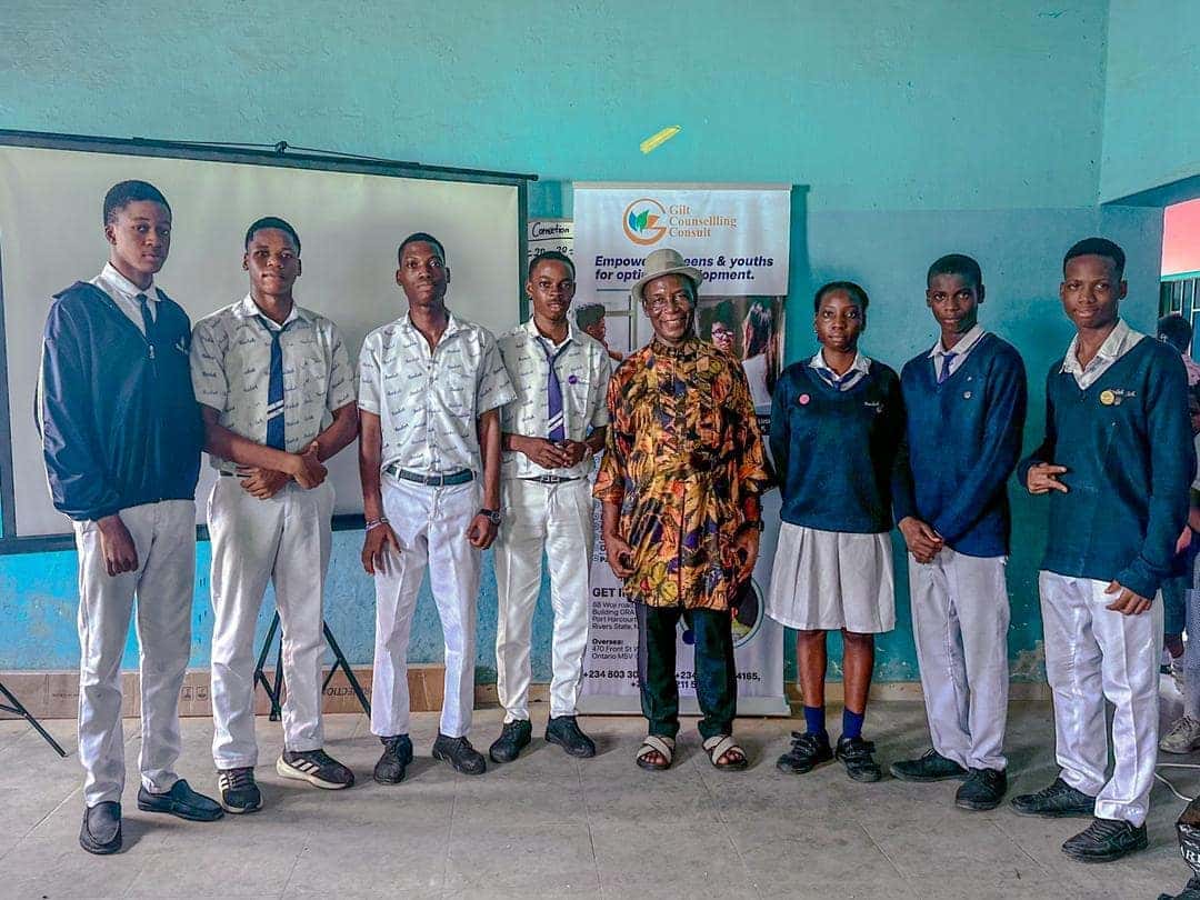 Gilt Counselling Consult facilitator with Great Beulah Heritage School students in front of the branded banner