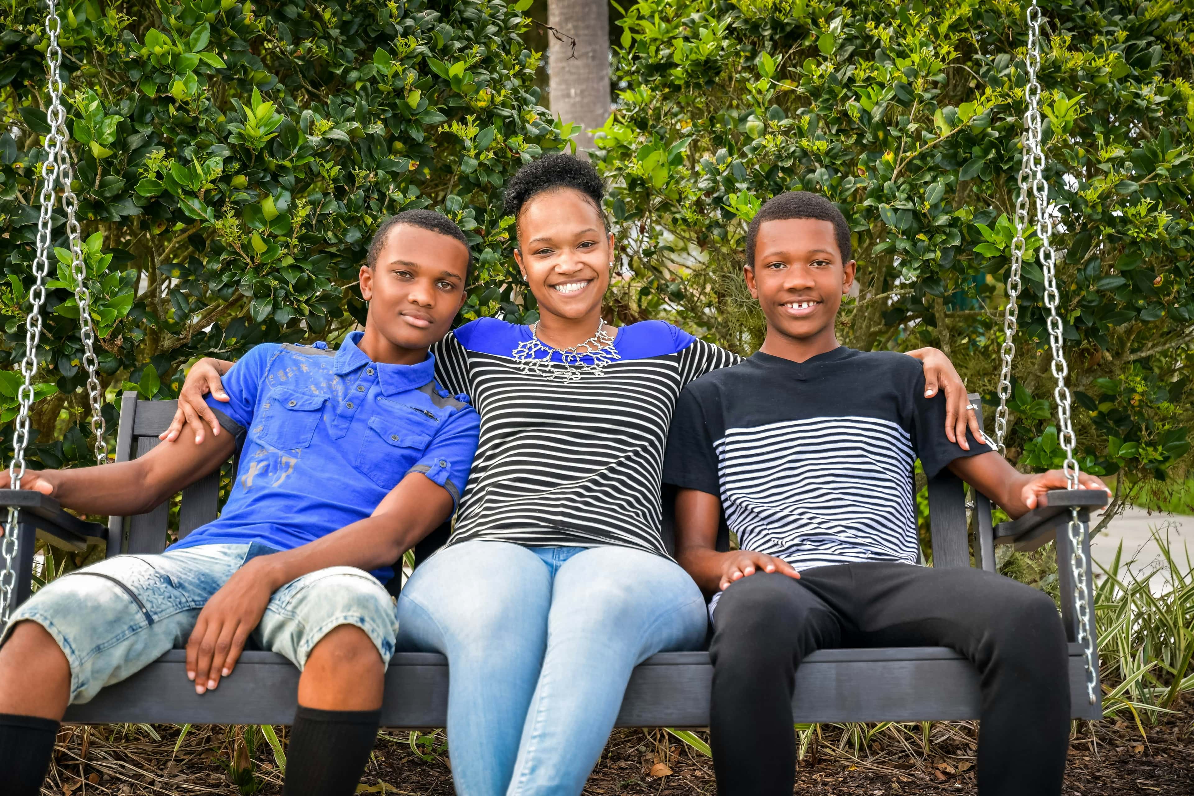 Mother with two teenage sons sitting together on a swing