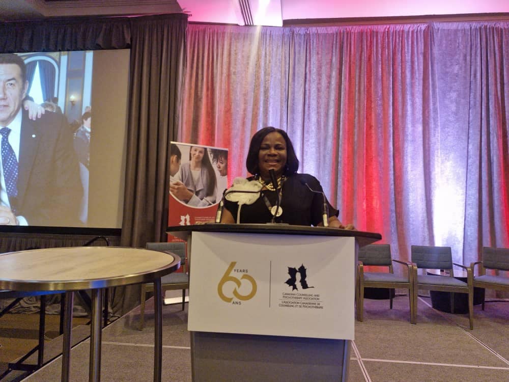 Dame Prof Chinelo Joy Ugwu speaking at the Canadian Counselling and Psychotherapy Association conference podium
